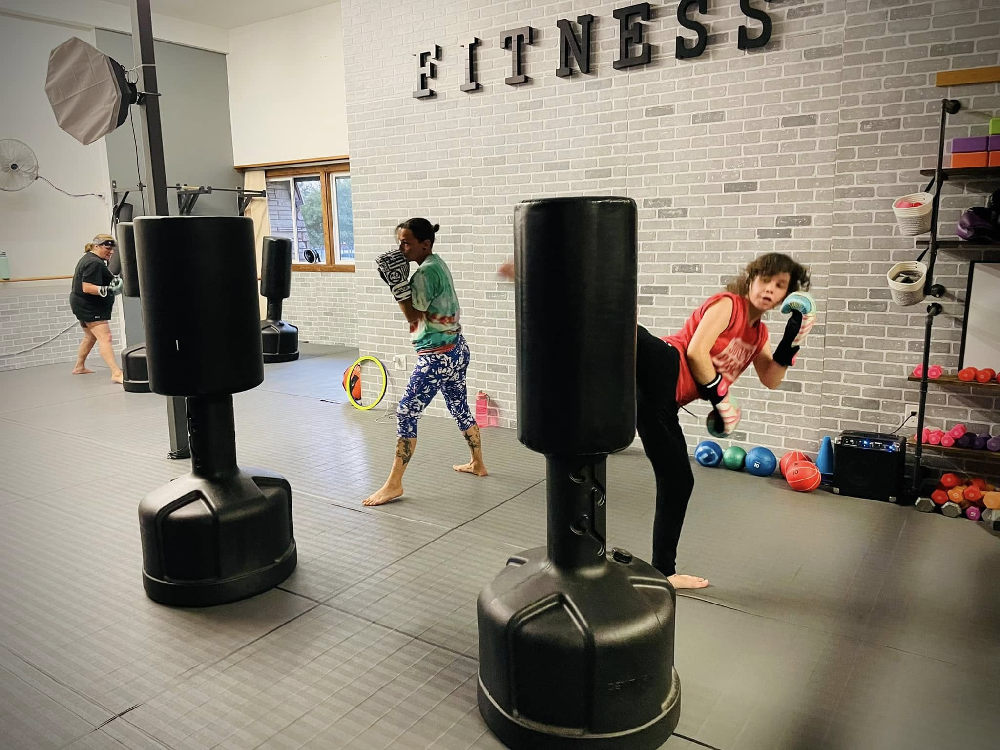 Women practicing kickboxing on fitness bags