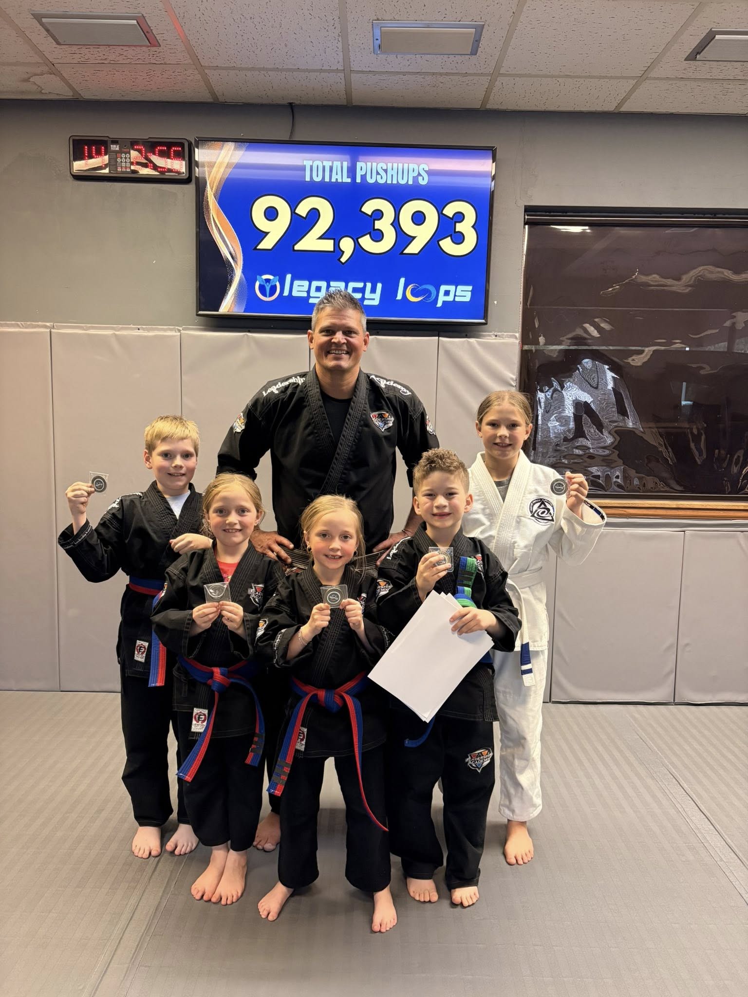 Leadership Academy students holding LEGACY coins with their instructor