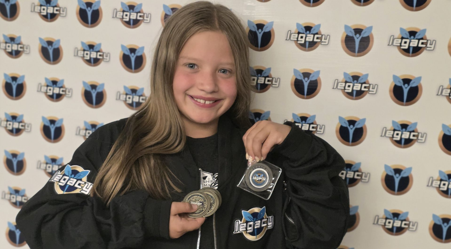 Student wearing LEGACY gear and holding earned coins