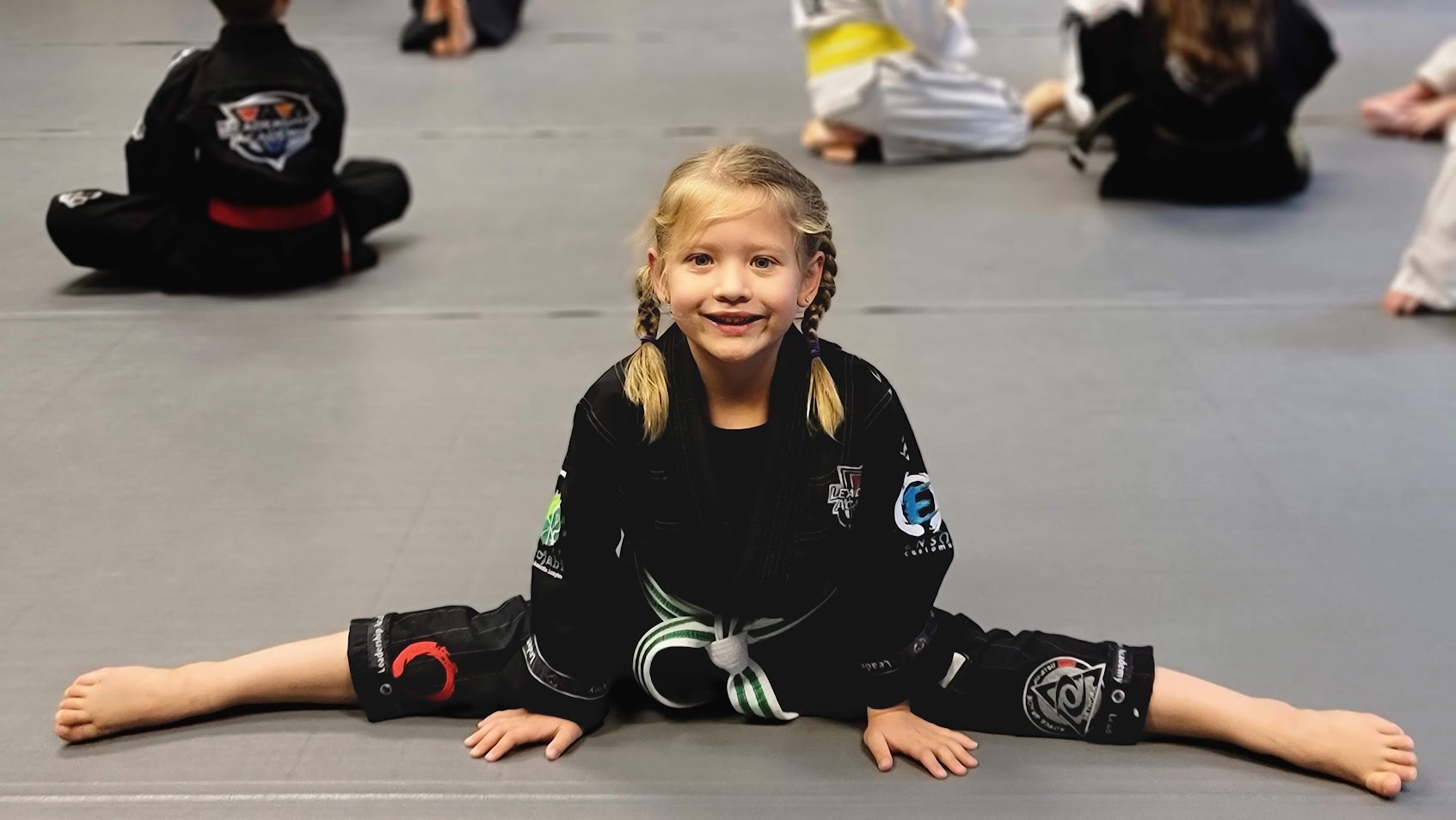 Lil Dragons student smiling during stretching on the mat